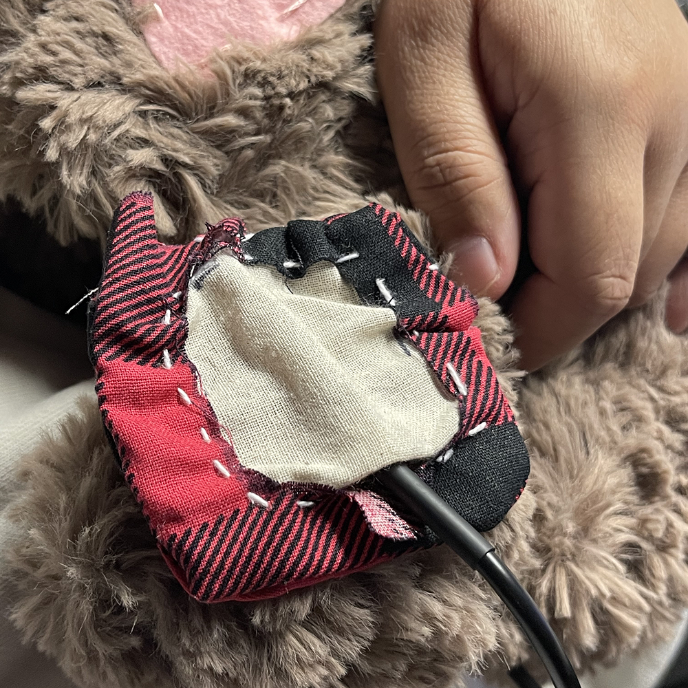 This is the badge on Miffy, threee things we needed to do was fix the entrance hole for the sensor, figure out a band to keep the patch on. Then discuss the appropriate fabric for the sensor. This was my job to determine and create what was needed (Wk 13 part 2)